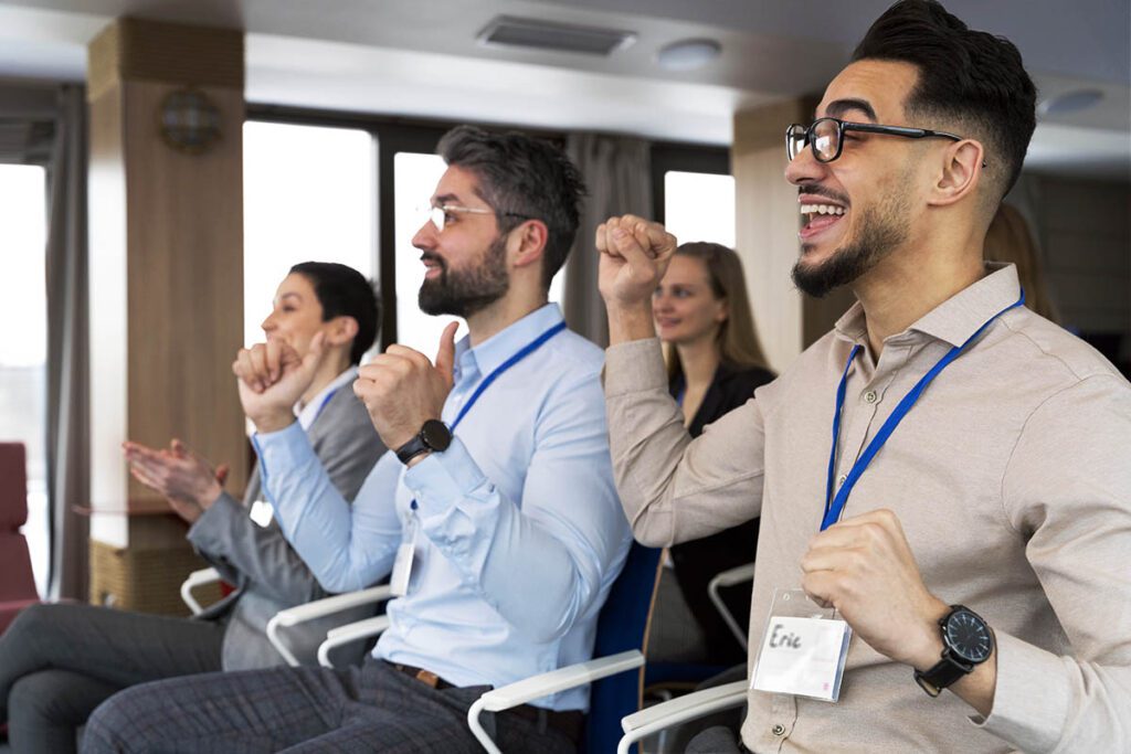 Group of conference attendees clapping and cheering. Image by Freepik.
